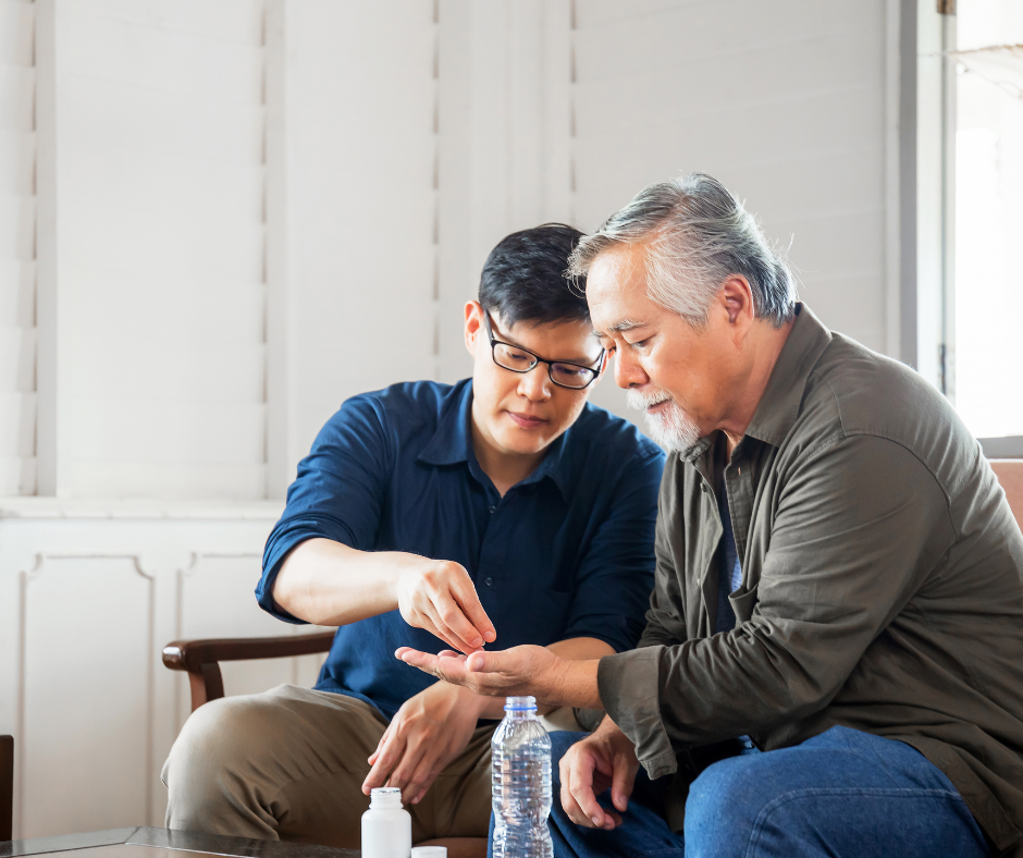 Son helping senior aged father take medication