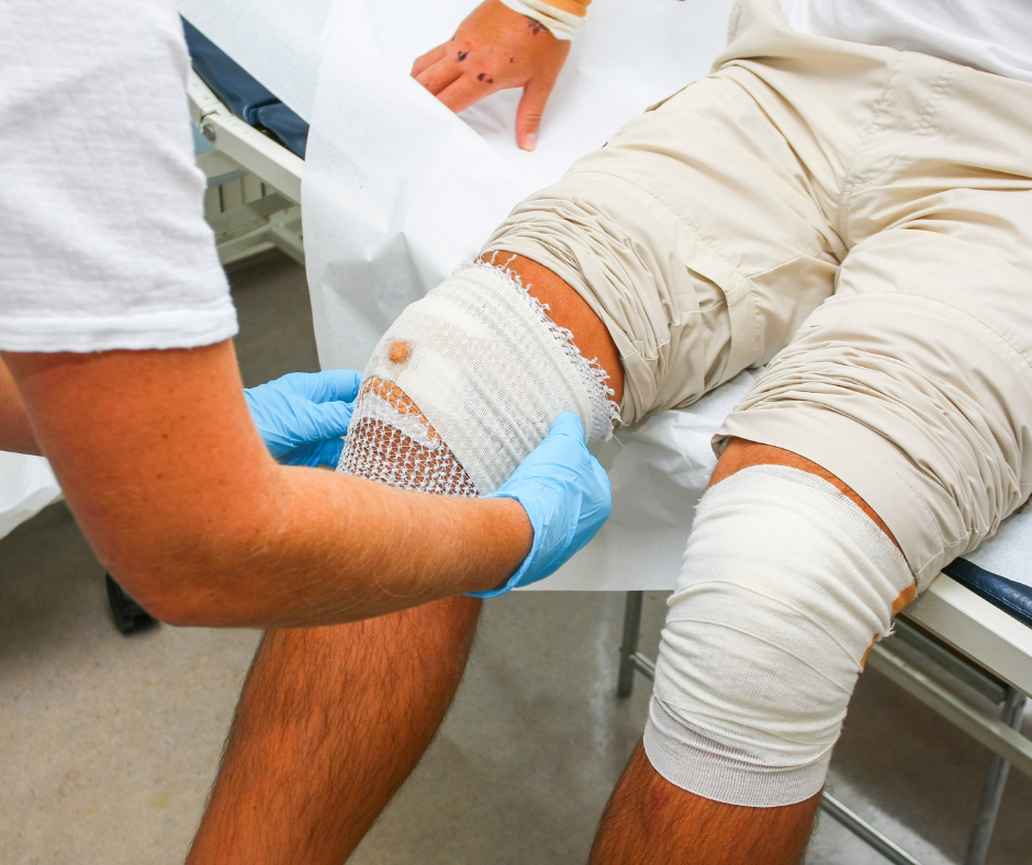 Nurse dressing wound on patient knee.